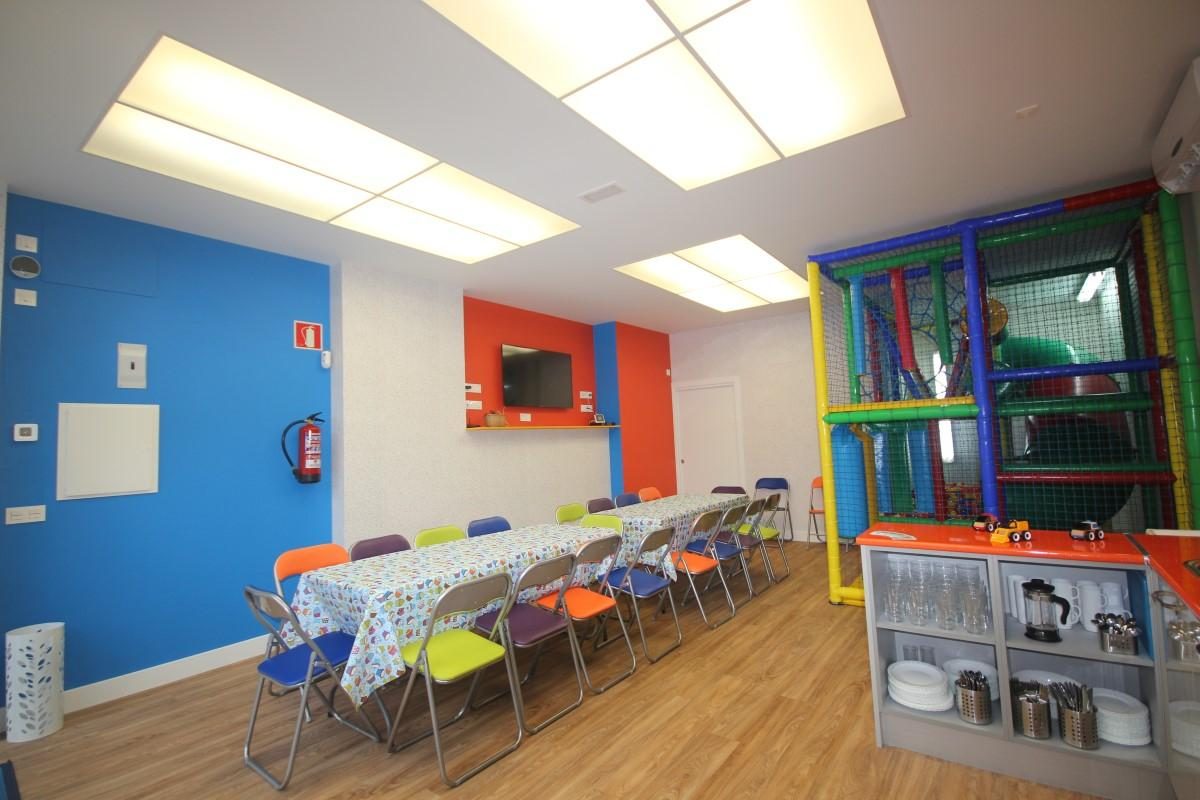 El comedor, con una mesa larga, sillas de colores y una pared azul